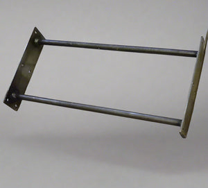 Metal bracket on a tiled floor with a ruler for scale