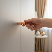 Load image into Gallery viewer, Hand opening a cabinet door with a gold handle, blurred background