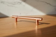 Copper cabinet handle on a wooden surface with a marble background