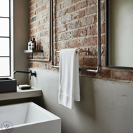 Copper and brass towel rail on a brick wall industrial themed bathroom