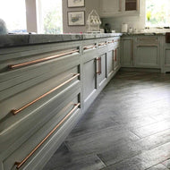 Modern copper cabinet handles mounted on a light grey cabinets. Elegant design with a satin polished finish.